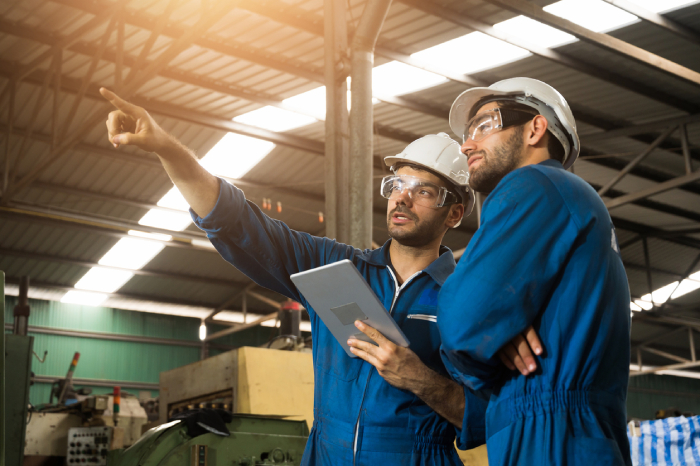 Two operators in a factory, using a tablet and finger pointing something far in front of them